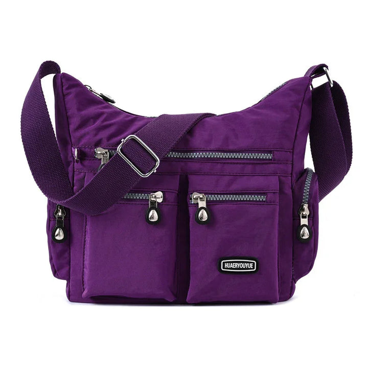 Purple crossbody nylon handbag with multiple zippered pockets and adjustable shoulder strap