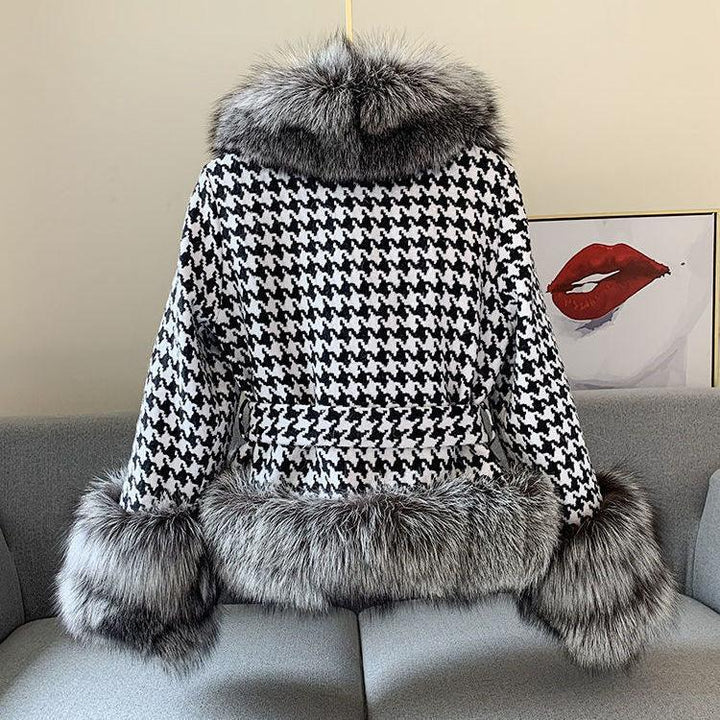 Black and white houndstooth coat with gray fur trim on collar, cuffs, and hem displayed on gray sofa