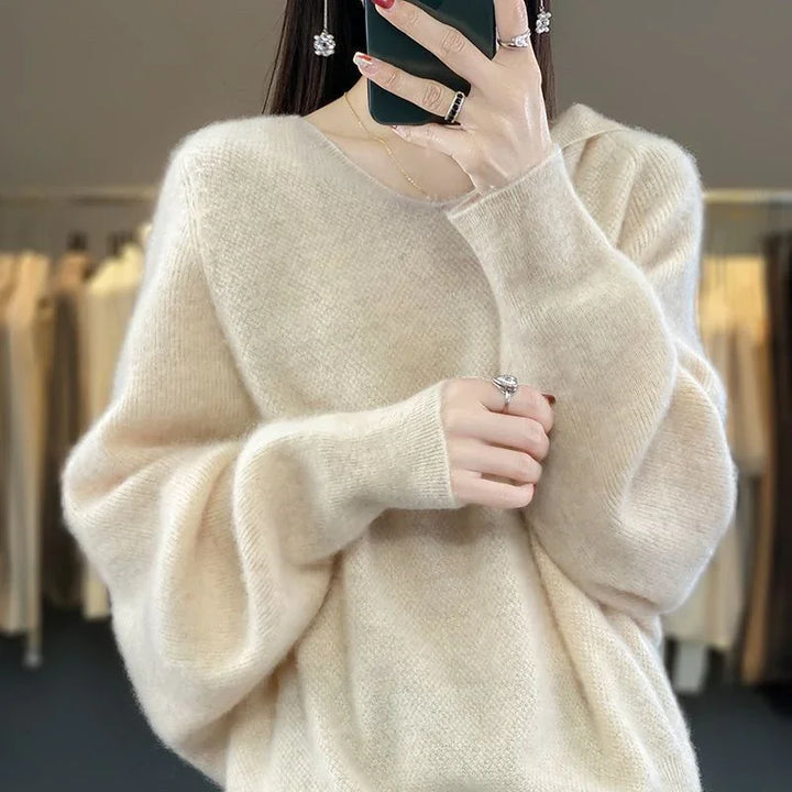 Woman wearing a soft beige fluffy oversized sweater taking a mirror selfie indoors