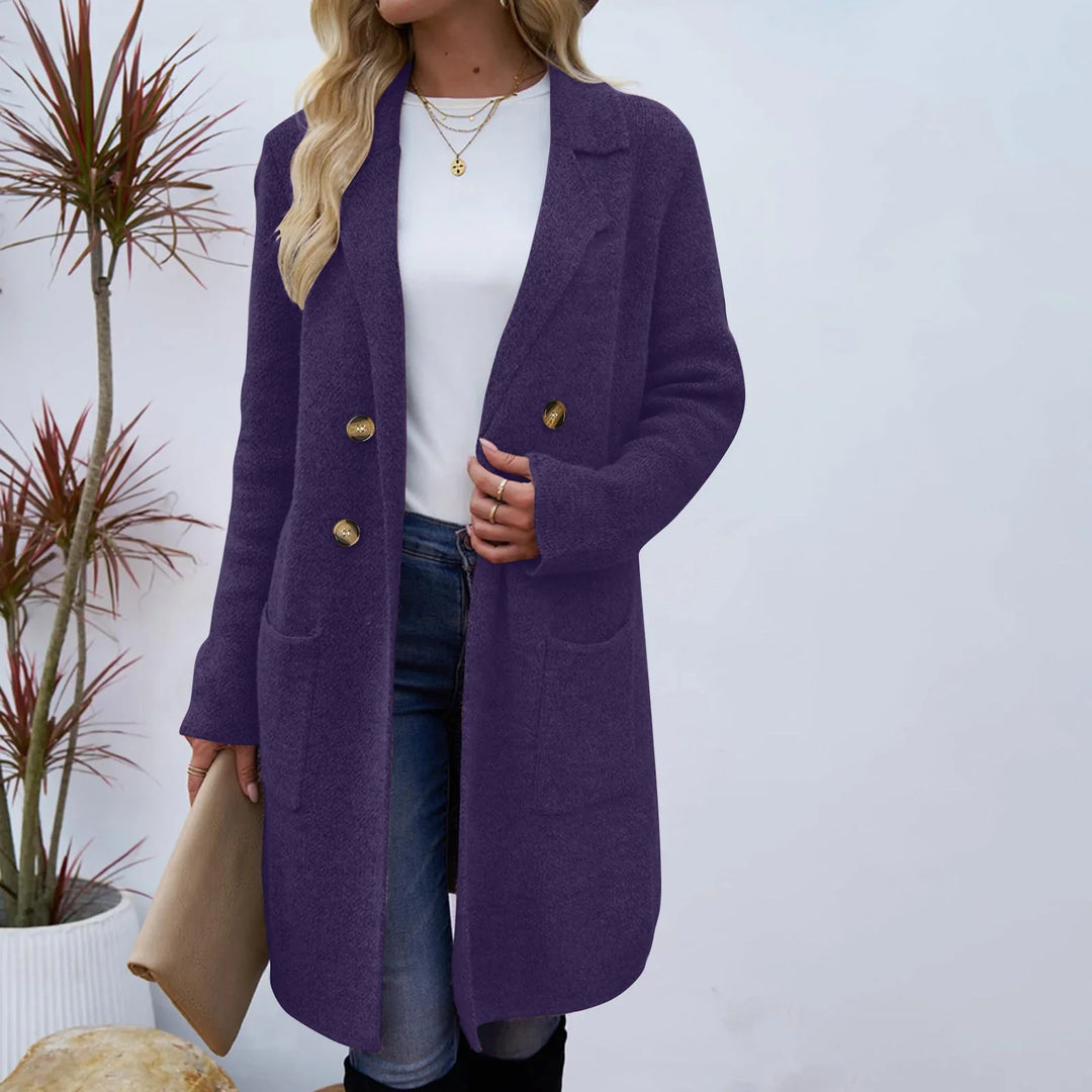Woman wearing purple wool long coat with gold buttons, white shirt, blue jeans, and gold necklaces