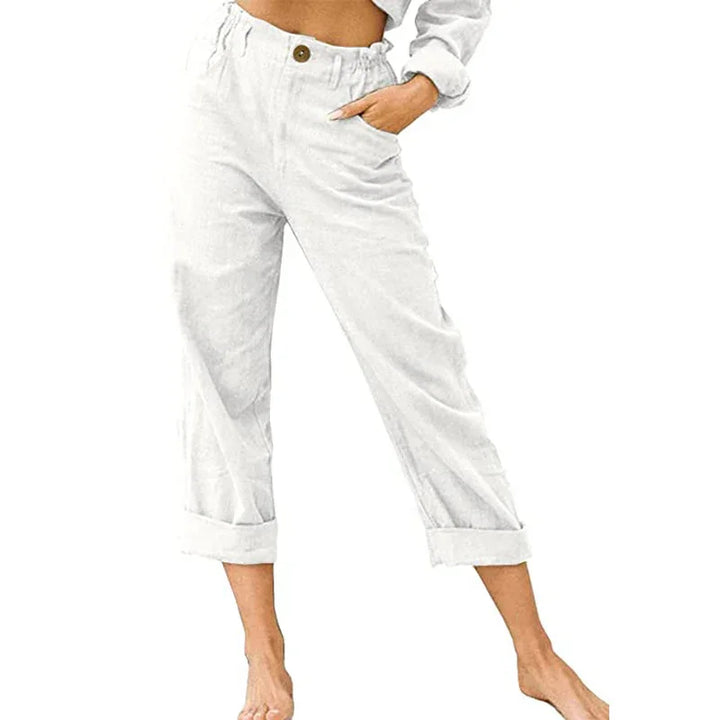 Woman wearing high-waisted white cuffed casual pants with button and pockets, barefoot