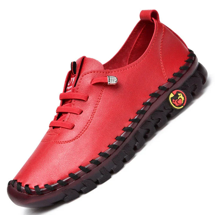 Red casual loafer shoe with black sole and stitching, featuring a small decorative emblem on the side