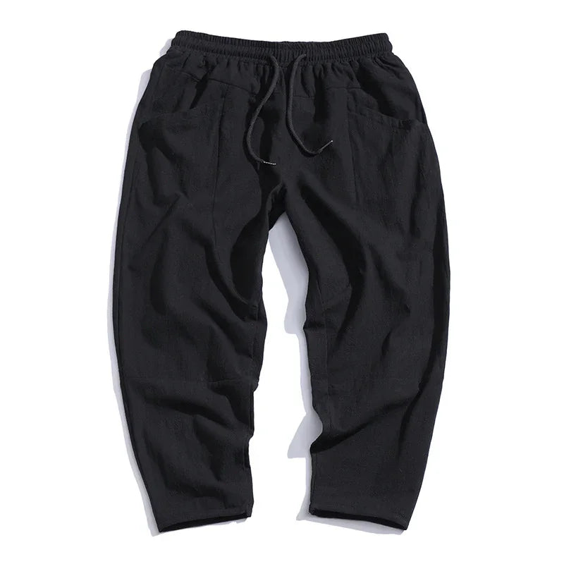 Black casual relaxed-fit pants with elastic waistband and drawstring, front pockets, and tapered legs