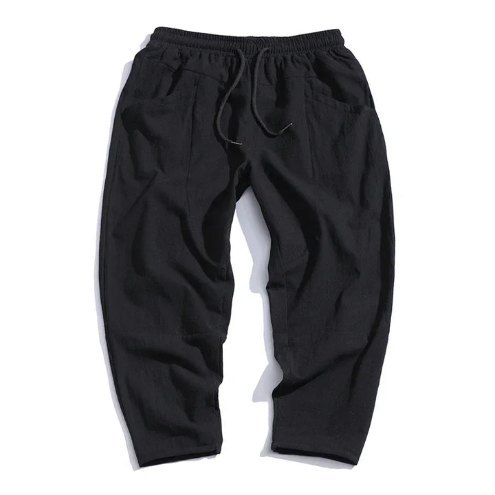 Black casual relaxed-fit pants with elastic waistband and drawstring, front pockets, and tapered legs
