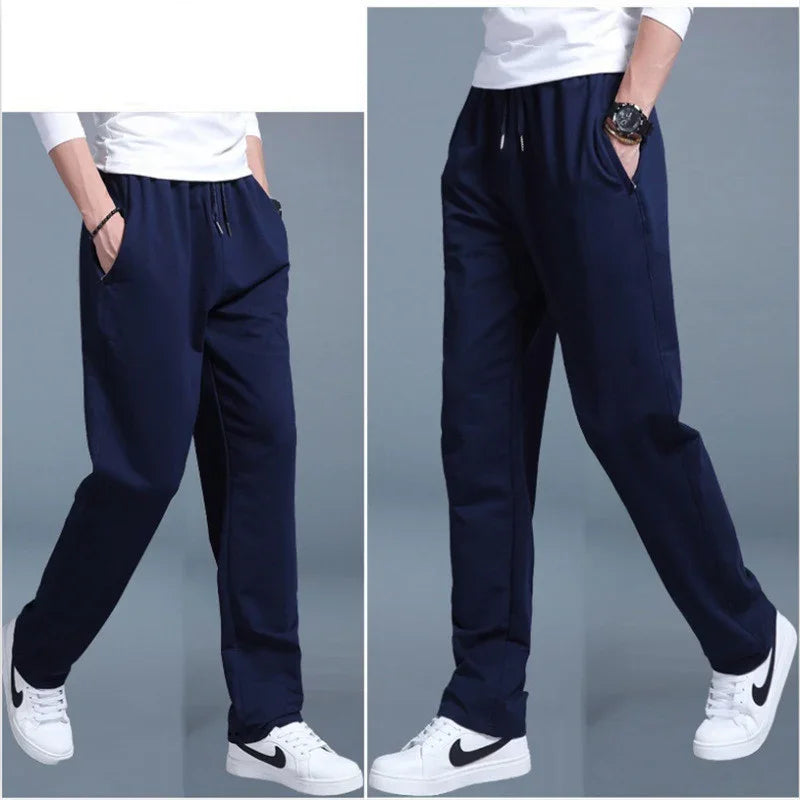 Men's navy blue casual jogger pants with elastic waistband and pockets, worn with white Nike sneakers