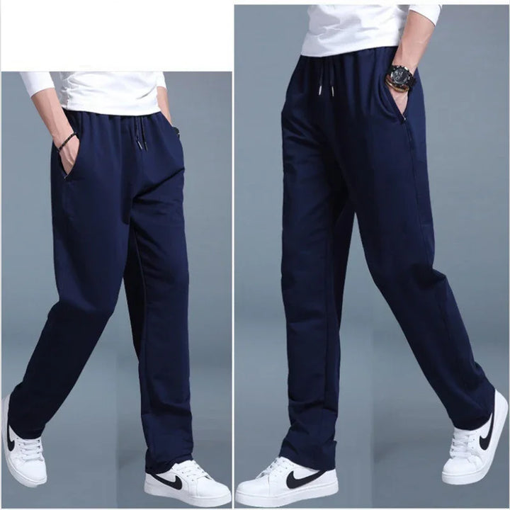 Men's navy blue casual jogger pants with elastic waistband and pockets, worn with white Nike sneakers