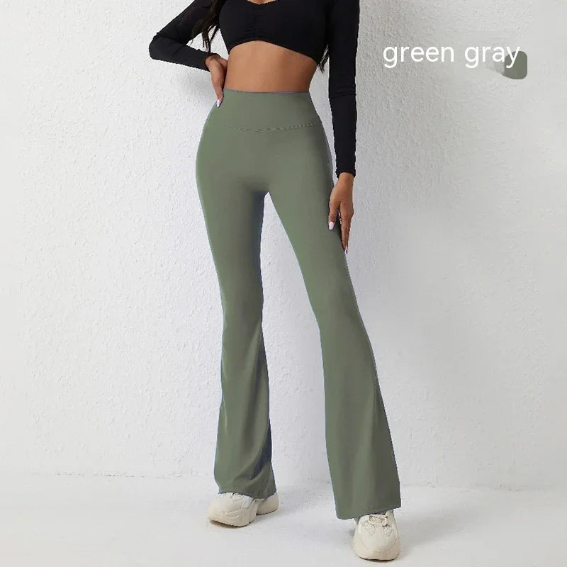 Woman modeling high-waisted green-gray flare leggings with black cropped top and white sneakers
