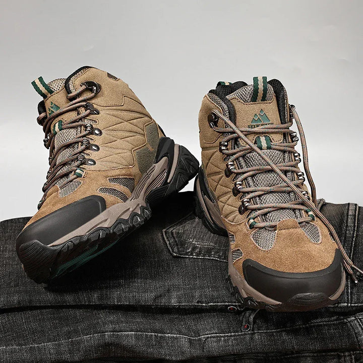 Pair of brown hiking boots with rugged soles placed on black denim fabric background