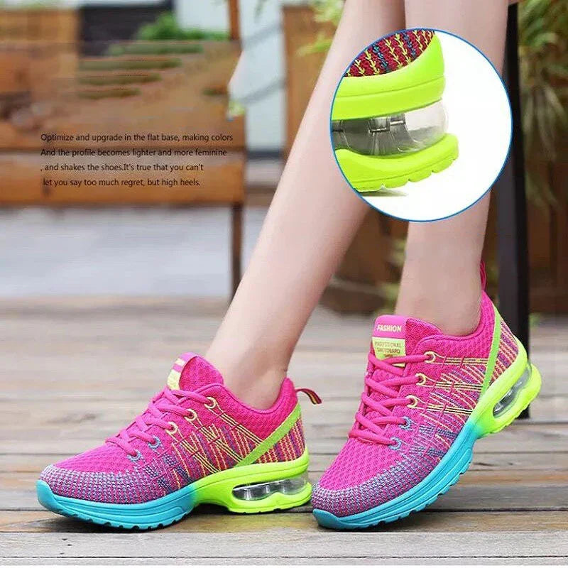 Bright pink and neon green women's sports sneakers with blue soles and air cushion soles on wooden floor