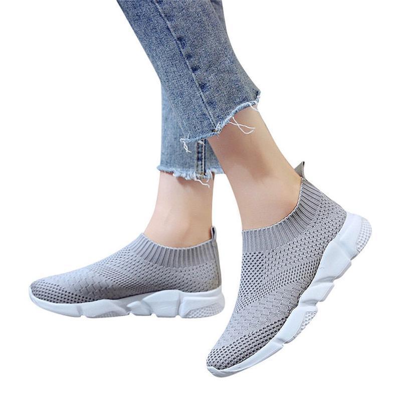 Light grey knit slip-on sneakers with white cushioned soles, worn with cropped frayed jeans