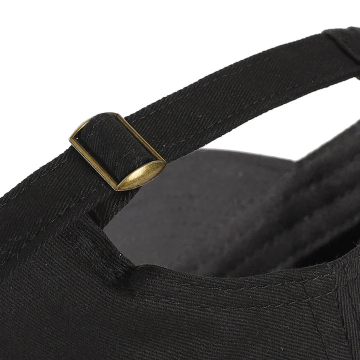Close-up of black adjustable fabric strap with metal buckle on a black cap