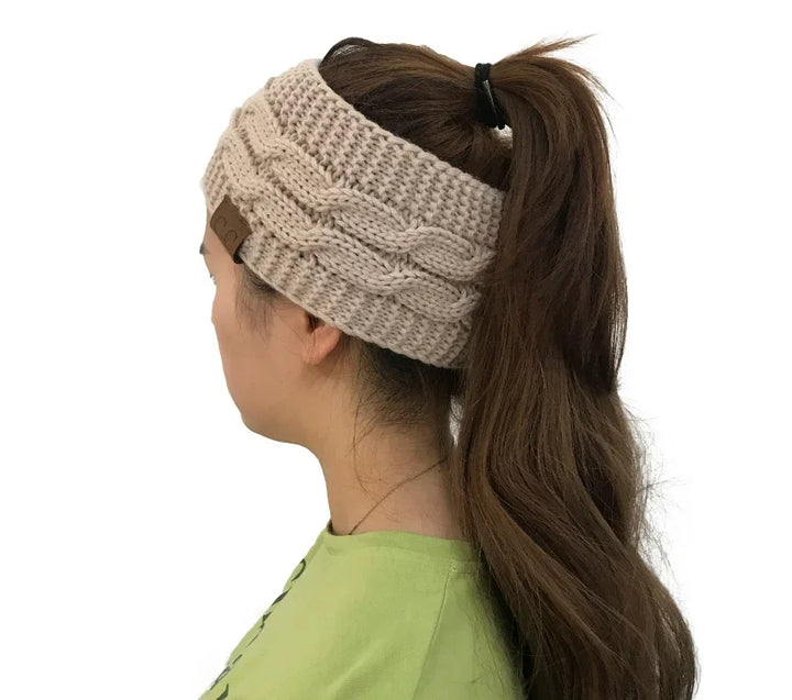 woman wearing beige knitted cable headband with ponytail and green shirt on white background