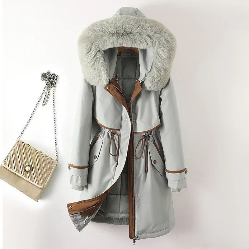 Light grey winter coat with large faux fur hood, brown trim, drawstring waist, and side pockets