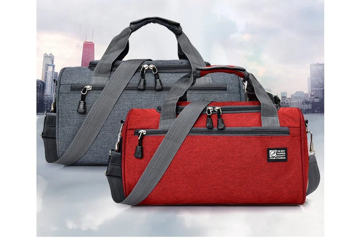 Red and gray travel duffle bags with multiple pockets and adjustable shoulder straps on cityscape background