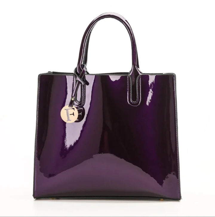 Glossy dark purple patent leather tote bag with top handles and gold charm detail