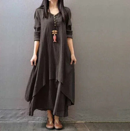 Woman wearing loose-fit long dark brown layered dress with long sleeves and wooden bead necklace