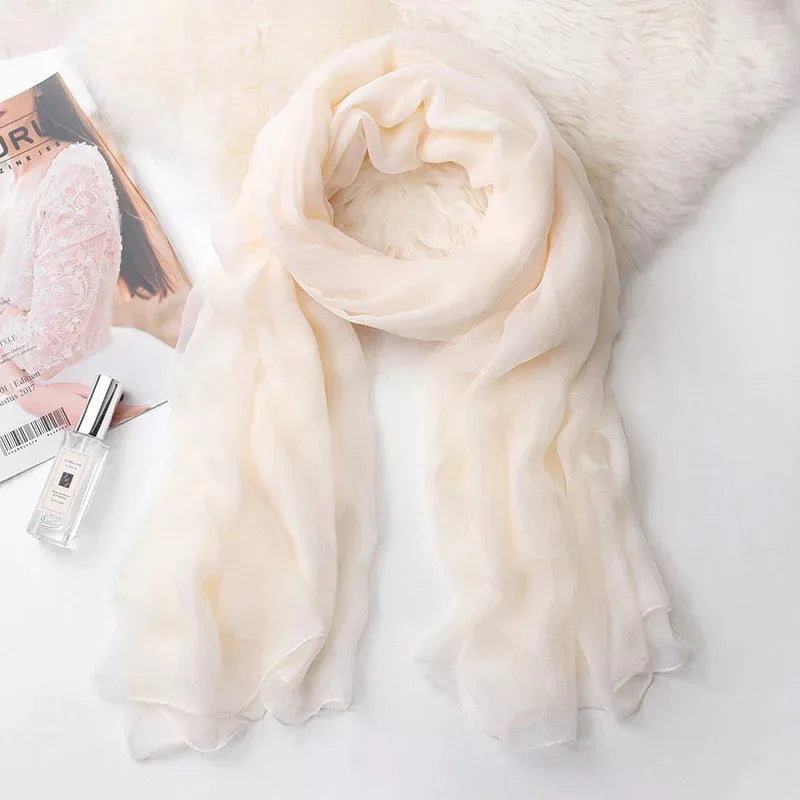 Soft beige chiffon scarf wrapped on white fur with magazine and perfume bottle