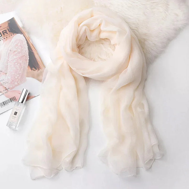 Soft beige chiffon scarf wrapped on white fur with magazine and perfume bottle