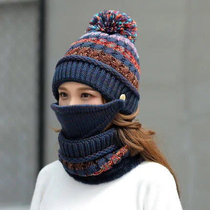 Woman wearing colorful knitted pompom beanie, navy face mask, and matching neck warmer in outdoor setting