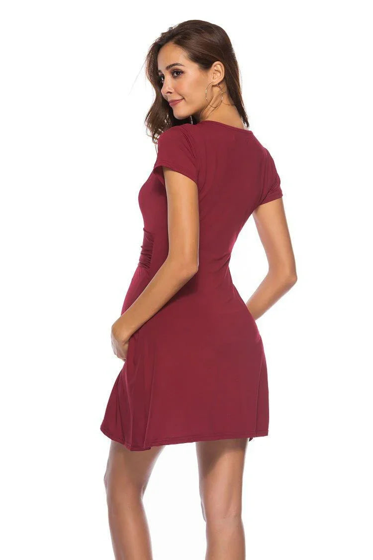 Woman wearing a fitted short-sleeve burgundy mini dress posing against white background