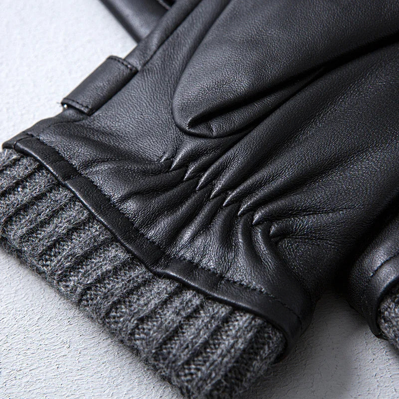 Close-up of black leather gloves with gray knit cuffs on a light surface