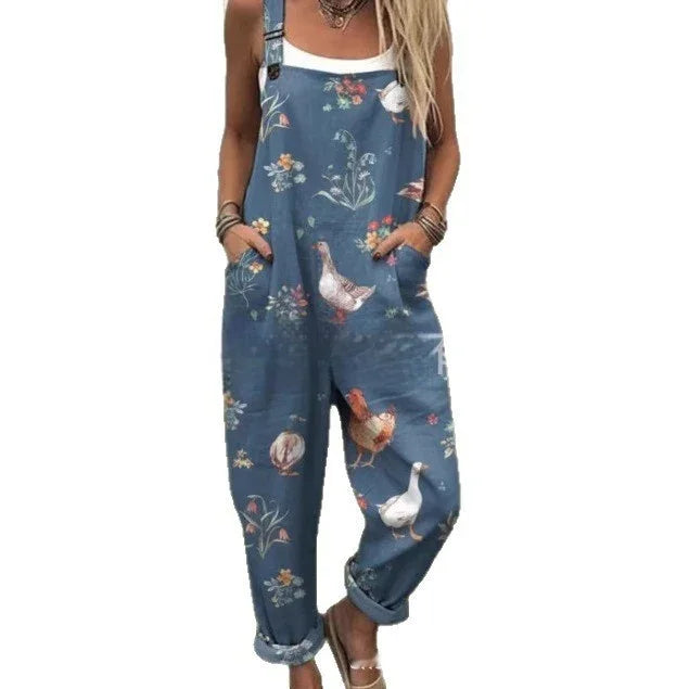 Woman wearing blue floral overalls with chicken and bird prints, styled with white tank top and sandals