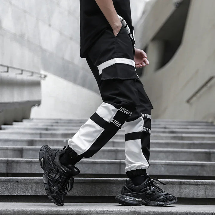 Person wearing black and white colorblock cargo pants with black sneakers walking down concrete stairs