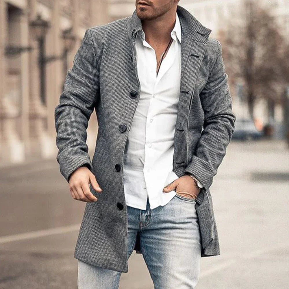 Man wearing a gray checkered coat over a white shirt and light blue jeans on a city street