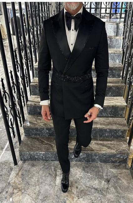 Man dressed in a black tuxedo with satin lapels and bow tie ascending marble stairs with ornate iron railings