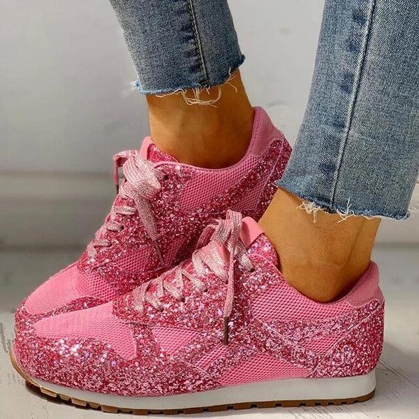 Pink glittery sneakers with mesh panels worn with frayed hem blue jeans on a light background