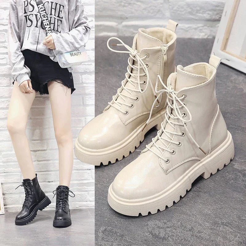 Pair of beige chunky lace-up combat boots with zipper side detail on gray floor