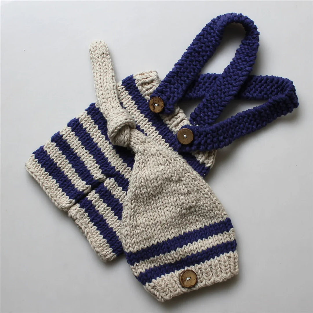 Handmade beige and navy blue striped knitted baby romper with wooden buttons on white background