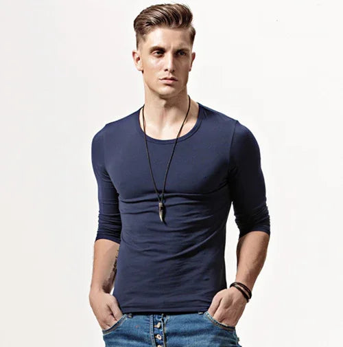 young man wearing navy blue fitted long-sleeve shirt with pendant necklace and jeans with buttons