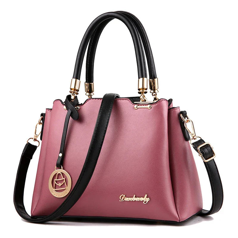 Elegant mauve leather handbag with black handles, gold hardware, and detachable shoulder strap