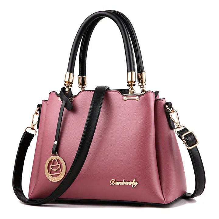 Elegant mauve leather handbag with black handles, gold hardware, and detachable shoulder strap