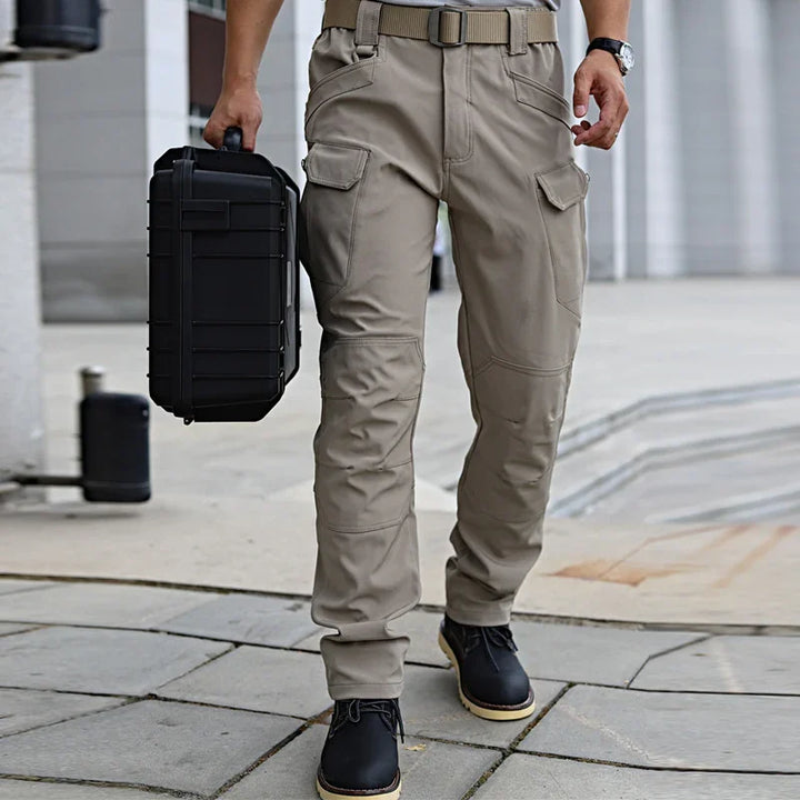 Man wearing beige tactical cargo pants and black boots carrying black hard case outdoors