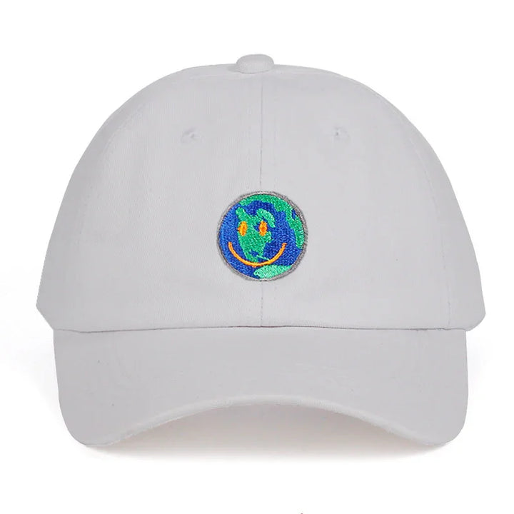 White baseball cap with embroidered smiling earth patch in blue, green, and orange colors