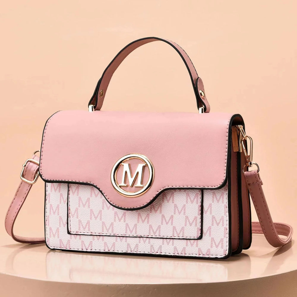 Pink leather handbag with gold 'M' logo, monogram pattern, top handle, and detachable strap