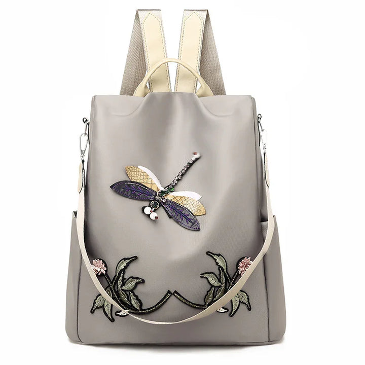 Gray backpack with dragonfly and floral embroidery, beige straps, and detachable shoulder strap