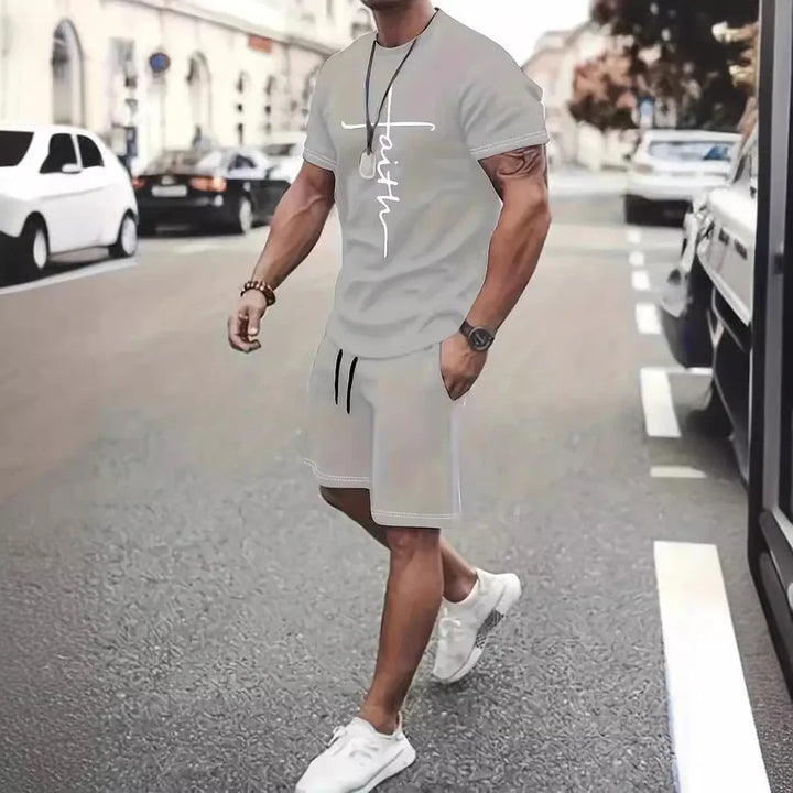 Man wearing gray faith graphic t-shirt and matching shorts walking on city street in casual outfit
