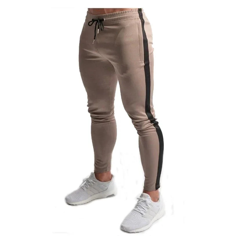 Men's slim fit beige jogger pants with black side stripe and drawstring waist, paired with white sneakers