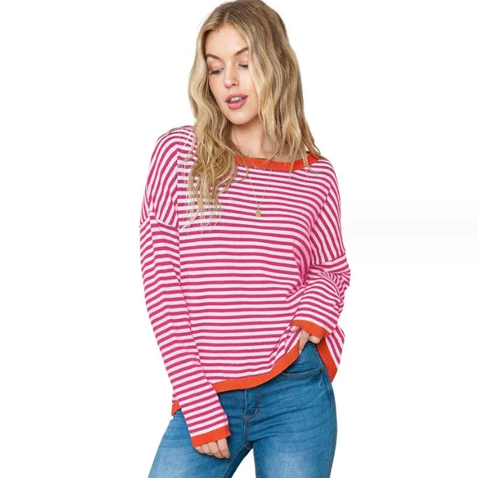 Woman wearing pink and white striped long sleeve sweater with orange trim and blue jeans