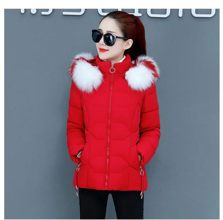 Woman wearing a red puffer jacket with white fur trim on hood and black sunglasses