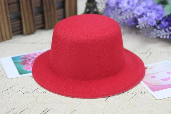 Bright red wool felt hat on a textured surface with floral cards and purple flowers in background
