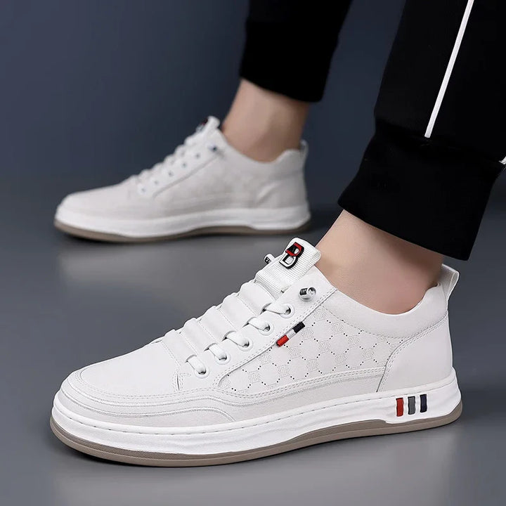 White men's casual sneakers with geometric pattern and red, black accents worn with black pants