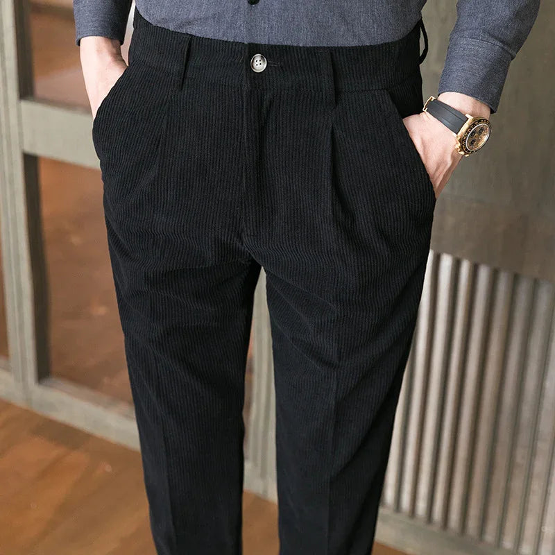 Close-up of man wearing black corduroy pants with hands in pockets and a gray shirt