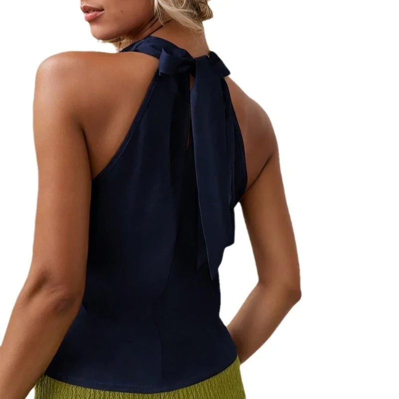 Woman wearing sleeveless navy blue halter top with bow tie back, paired with olive skirt
