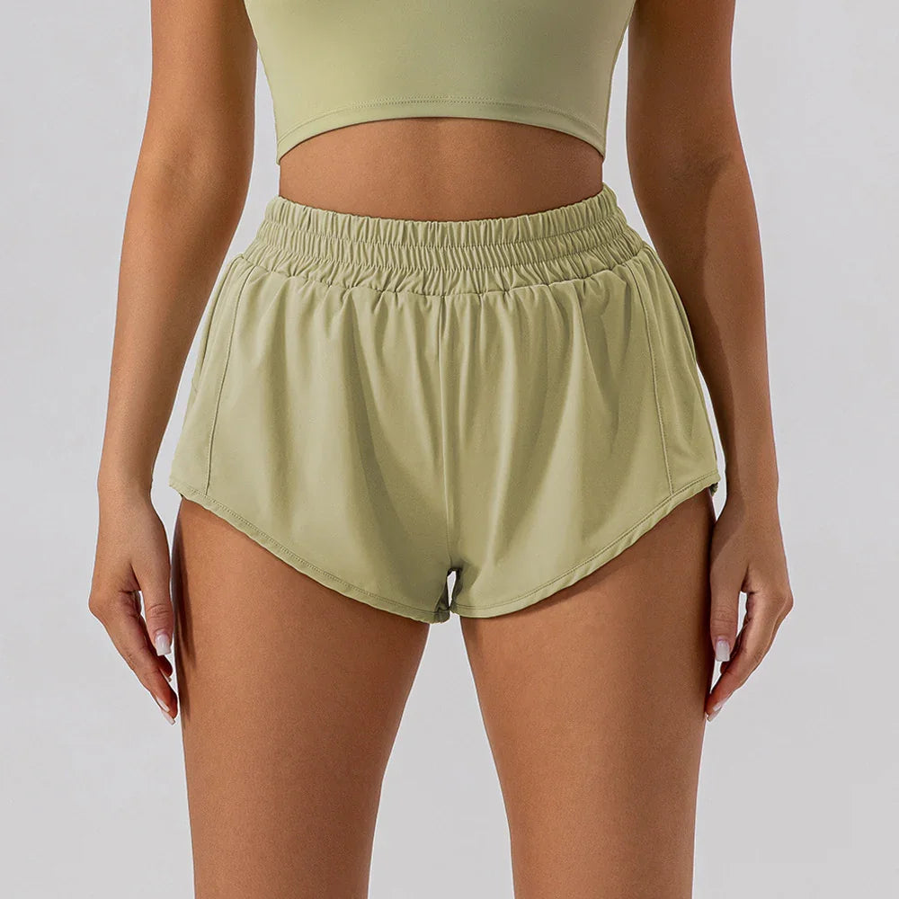 Woman wearing light green elastic waist running shorts and matching sports bra