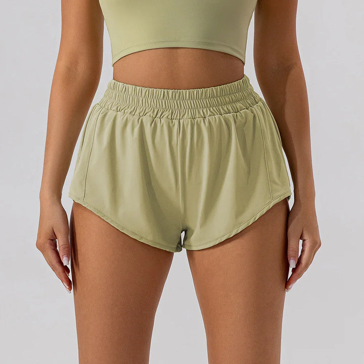 Woman wearing light green elastic waist running shorts and matching sports bra