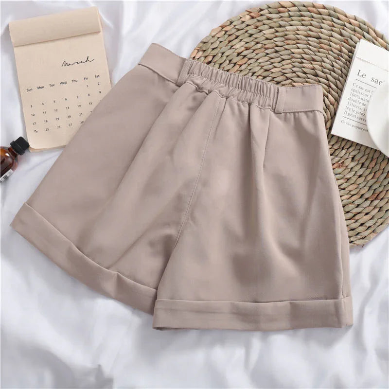 Beige casual shorts with elastic waistband on white fabric with woven placemat and calendar